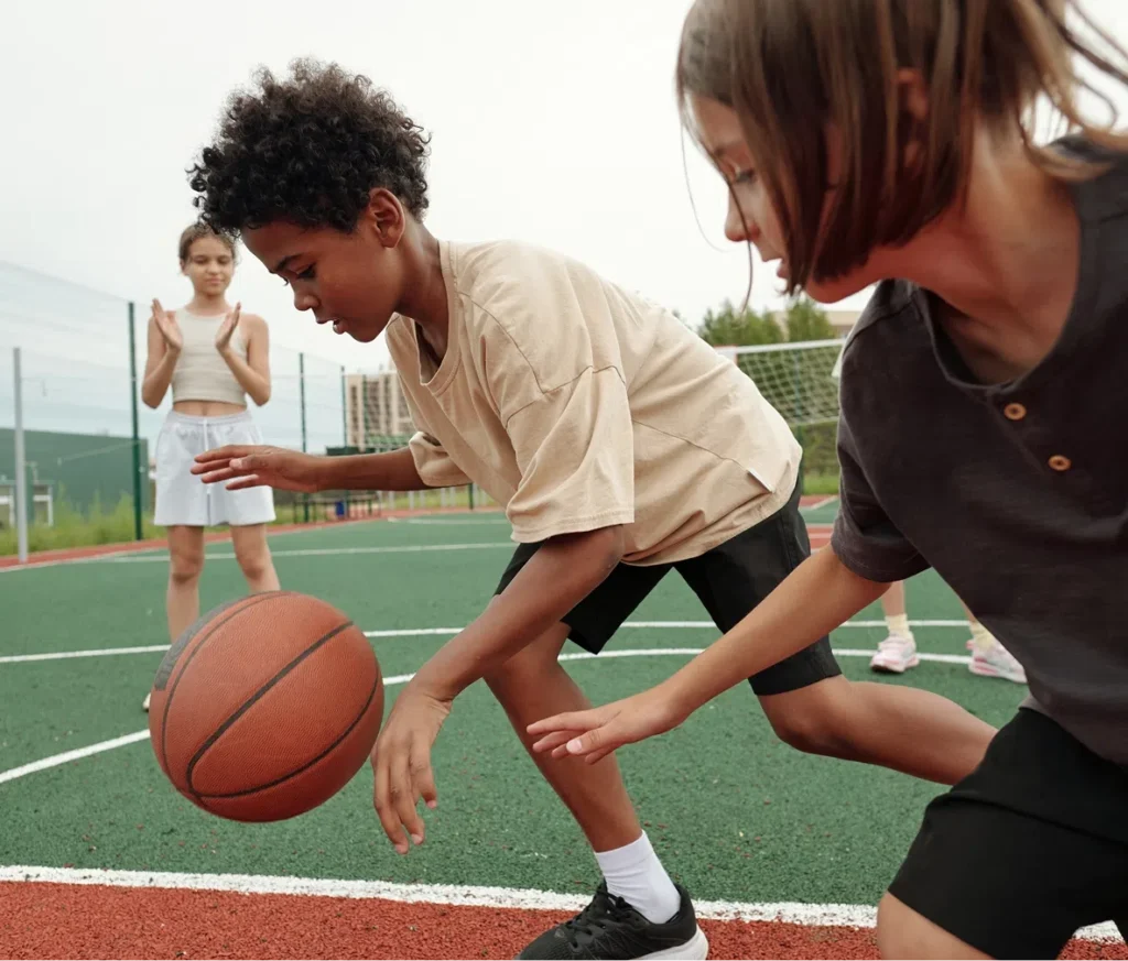 Two kids playing basketball, showcasing the impact of donations to Playground Stars in providing access to youth sports.