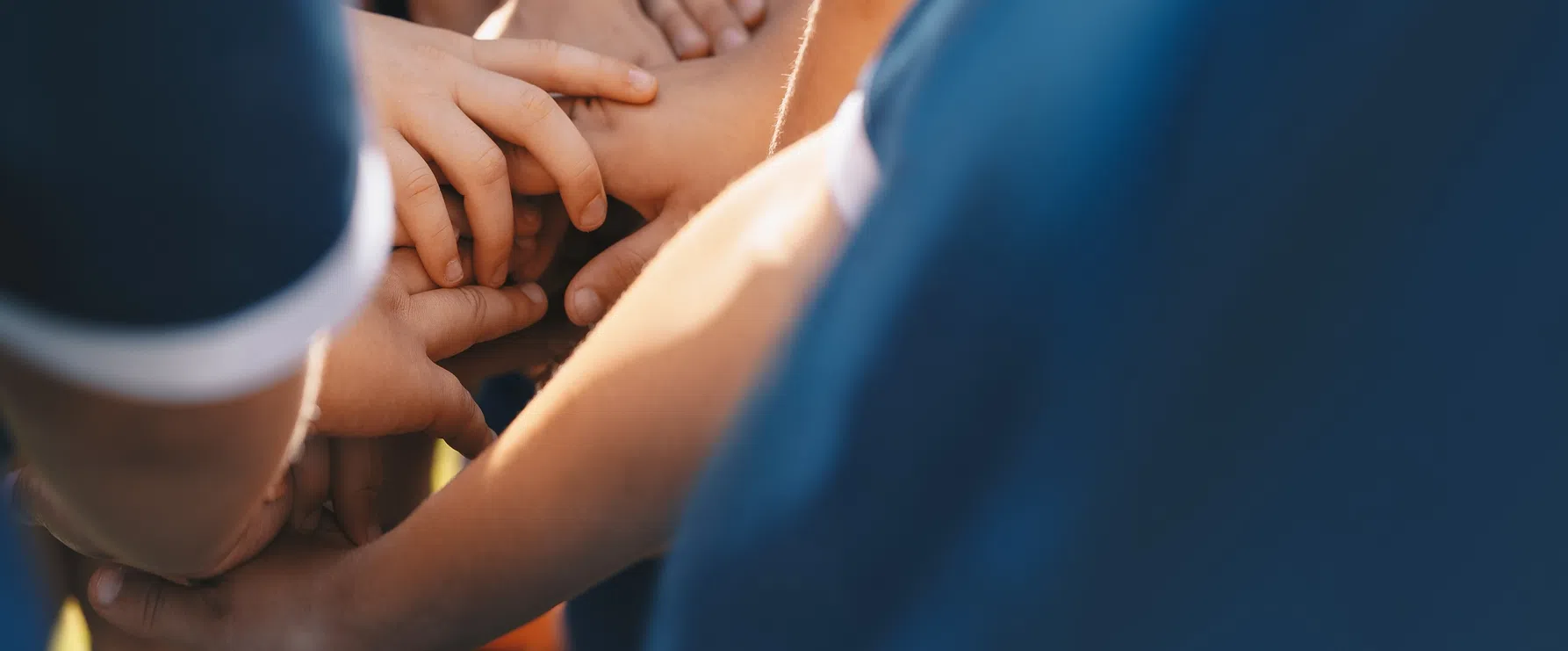 Hands stacked together, symbolizing unity and teamwork in youth sports, made possible through donations to Playground Stars.